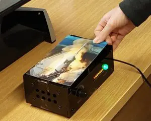Picture of a hand placing a postcard onto the top of the Museum in a Box
