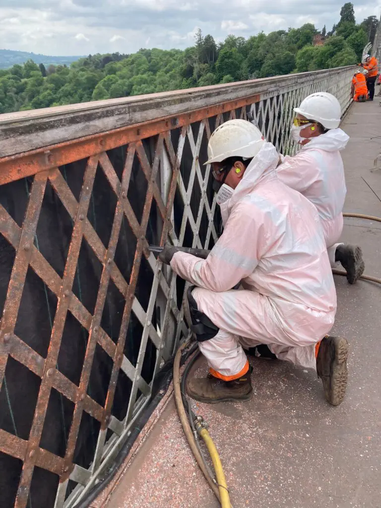 Painting team removing old paint from ironwork